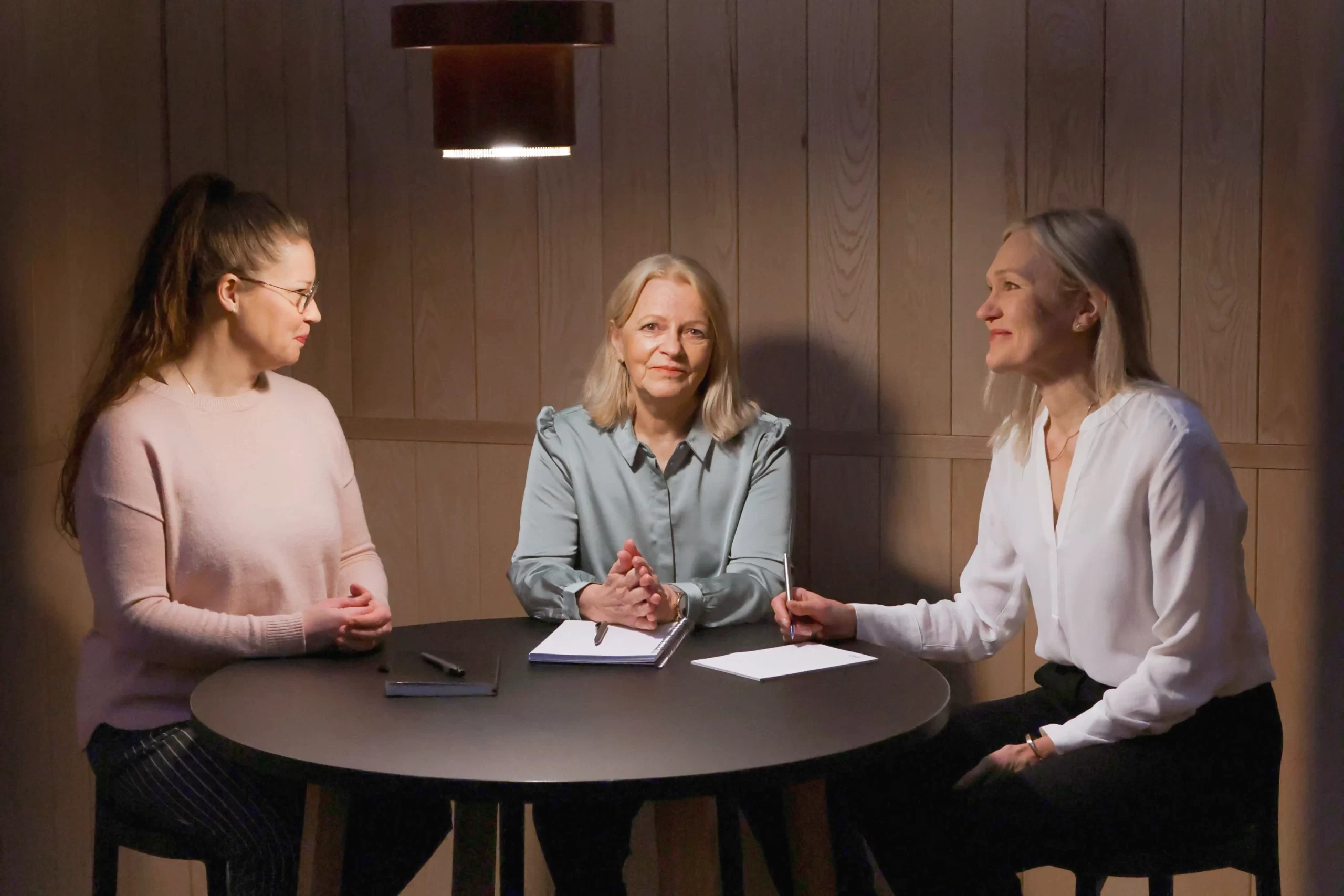 Kolme naista keskustelemassa työpöydän ääressä