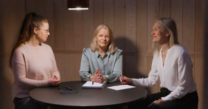 Kolme naista coaching-keskustelussa työpöydän ääressä